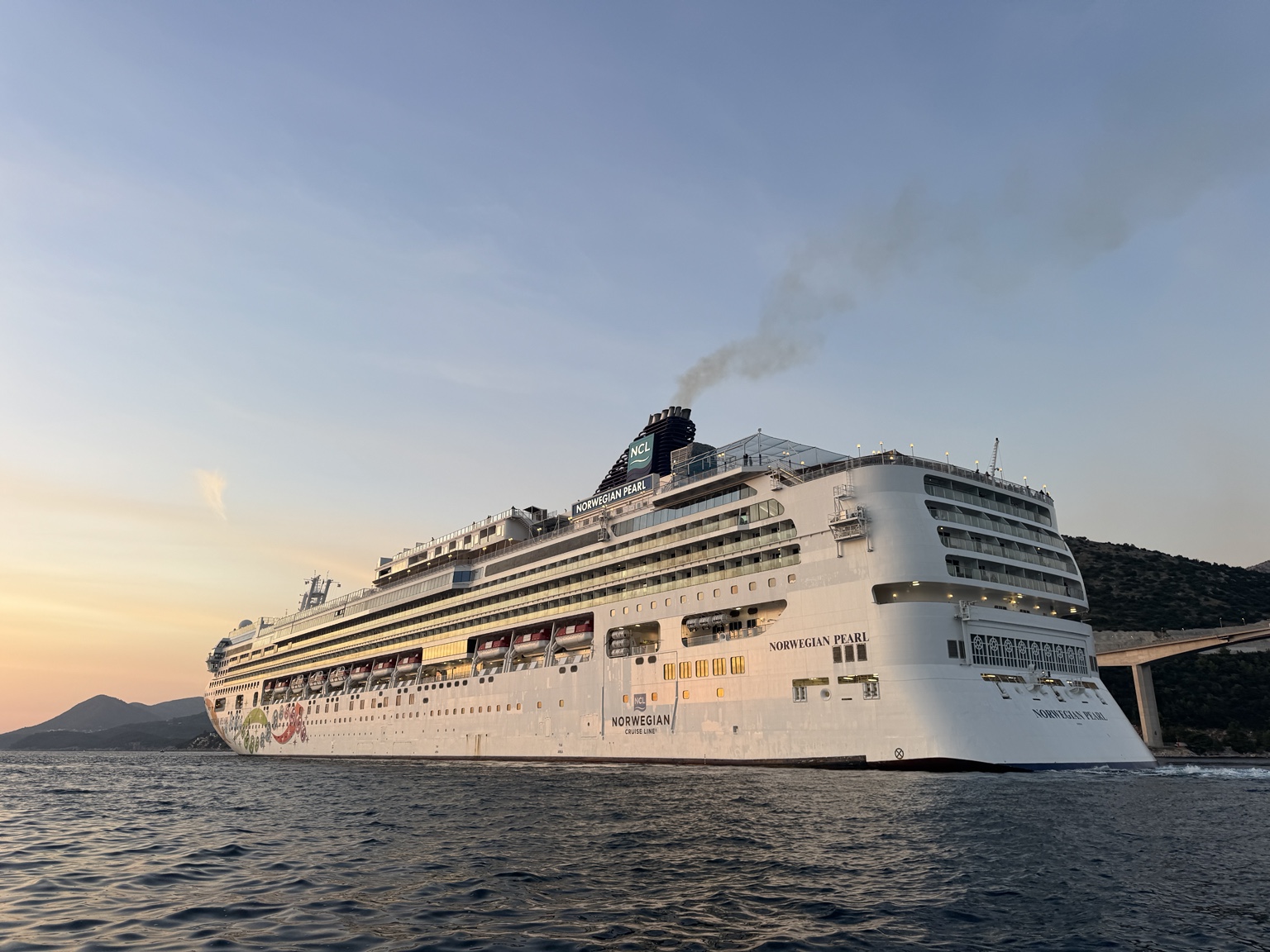 Norwegian Pearl u akvatoriju Gruža, uz Most dr. Franja Tuđmana, pri zalasku sunca; širi bočni kadar. Izvorna datoteka IMG_2879.jpeg.